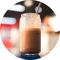 Latte frío servido en vaso de vidrio con bombilla reutilizable sobre fondo desenfocado