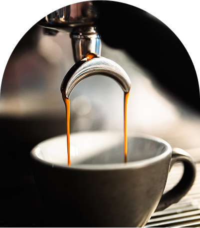 Persona bebiendo café en taza gris mientras se sienta frente a una mesa blanca con bandeja de madera vacía